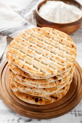 Fresh baked greek pita bread on white wooden background.