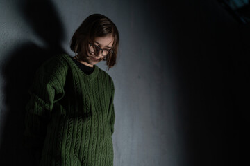 Sad little girl, alone in darkness, standing and thinking.