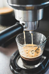 coffee machine pouring double espresso shot in clear coffee glass, coffee break at home