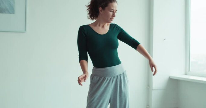 Dance therapy. Fitness leisure. Home training. Freedom wellbeing. Inspired graceful woman enjoying relaxing movements in light studio interior.