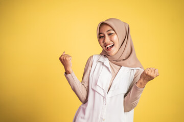 woman in hijab clenching hands while celebrating success