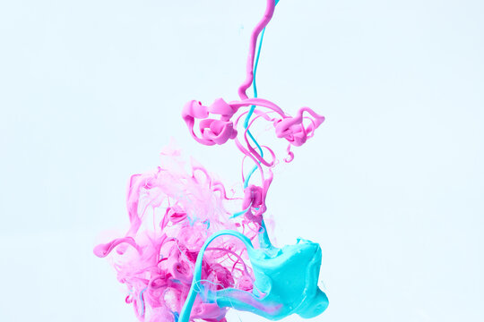 Paints splash curves in water on white. Acrylic paint drop background. Abstract pink and blue colors swirl texture