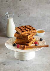 Waffles with raspberries, blueberries and honey on concrete background