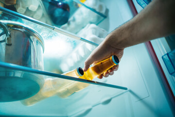 Close up man's hand takes a bottle of beer out of the fridge
