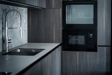 Modern dark grey kitchen design - detail of interior with steel faucet and home appliances
