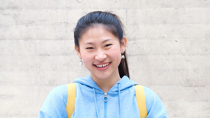 Young Asian college student woman looking at camera smiling,