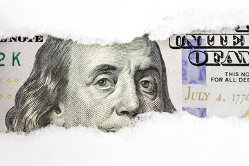 Portrait of US president Benjamin Franklin on 100 dollars banknote in torn paper hole. Hundred...