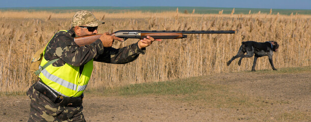 Hunter man in camouflage with a gun during the hunt in search of wild birds or game. Autumn hunting...