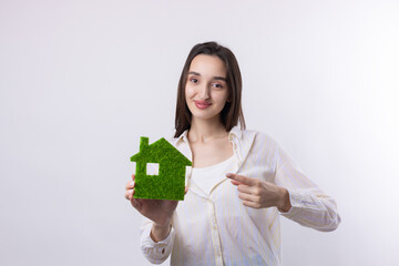 A young girl realtor holds a model of a green house in her hands. Sale of ecological real estate.