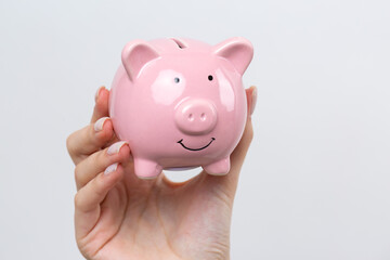 3d pink piggy bank in the beautiful hands of a girl..Close-up photo on a white background.