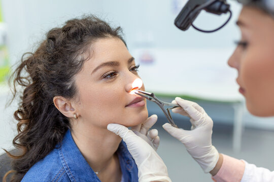 Otolaryngology concept. Positive woman otorhinolaryngologist checking nose with otoscope of his patient at hospital. Nasal congestion, sinusitis, allergy concept. Female patient at modern ENT clinic.