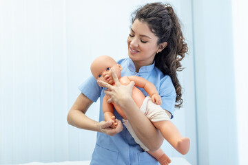CPR practitioner examining airway passages on infant dummy. Model dummy lays on table and two doctors practice first aid.