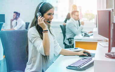 Confident young woman in headset, sitting in office, working as operator of call center or support...