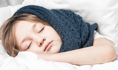 Little girl sleeps under white blanket. The warmth of home comfort.