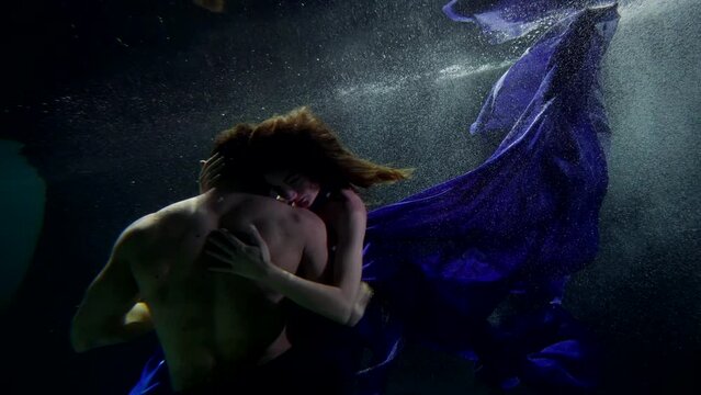 muscular man is embracing his graceful woman underwater, romantic fantasy and dream