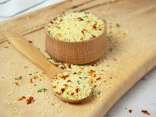 couscous mix with spices and tomatoes in a wooden bowl and spoon close-up