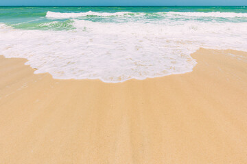 Ocean water foam splashes washing sandy beach. Amazing landscape scenery. Crashing waves of sandy coastline. Sea ocean water surface with small waves. Beautiful nature background with copy space