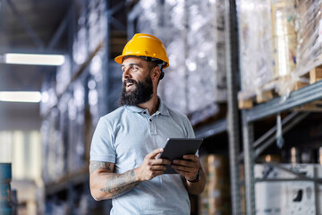 An inspector stands in the warehouse and checks on inventory on the tablet. 