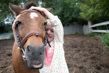 girl hugging pony horse muzzle at ranch