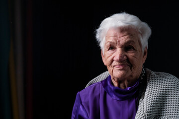 Portrait of serious senior woman against black background