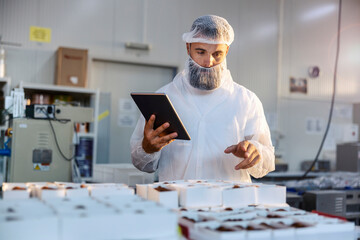 A supervisor in a food factory and counting boxes with collected cookies. 