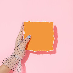Spring creative layout with hand in lace glow holding bright orange torn paper and pastel pink...