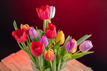 a big bouquet of tulips of various colours in crystal vase