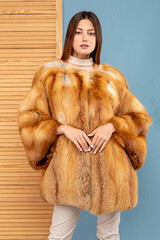 A beautiful girl with dark hair poses in a fur coat