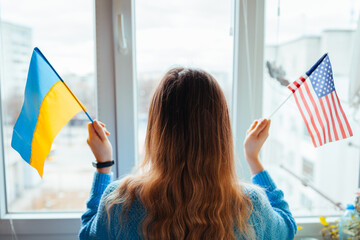 Woman holding ukrainian and american flags during war with Russia. Invasion in Ukraine. 2022...
