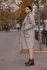 Fototapeta premium Fashionable girl walking down the street in a European city in a stylish coat