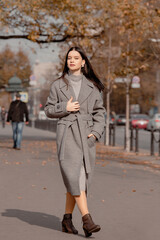 Obraz premium Fashionable girl walking down the street in a European city in a stylish coat