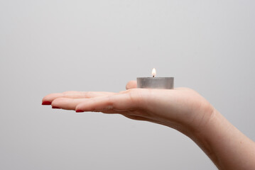 Mano de mujer joven sosteniendo una pequeña vela en una caja metálica en la palma de su mano con...