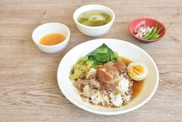 braised  slice pork leg stew black Chinese herb soup topping brown boiled egg half cutting eat couple pickled cabbage and kale dipping  mixed spicy sour chili sauce on plain rice in white plate