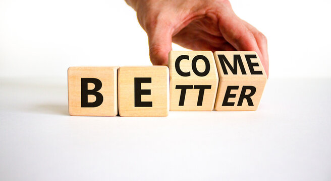 Become better symbol. Businessman turns wooden cubes and changes the concept word Better to Become. Beautiful white table white background. Business become better concept. Copy space.
