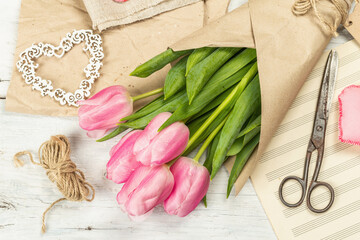 Bouquet of fresh pink tulips. Making spring floral decorations. Tools, vintage scissors, craft paper