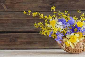 spring flowers in basket on wooden background