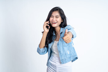 Fototapeta premium Young asian woman making a call using a mobile phone with thumbs up