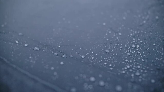 Close-up shot of raindrops water droplets on the tent. Dew drops on texture of fabric of tourist tent in rays of rising or setting sun. Camp, hiking tourism. The rain is pounding on tent. Slow motion