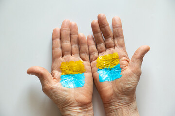 The flag of Ukraine yellow-blue is drawn on the hands of an old woman, Stop the war and patriotism, peace in Ukraine, war