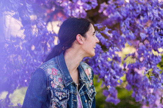 Side on profile of happy woman laughing in spring with background of purple jacaranda flowers