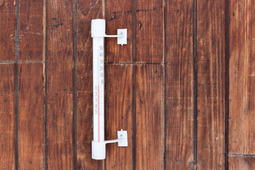 Thermometer hanging on a wooden wall in the street. Temperature 0 degrees on a outdoors thermometer with a Celsius scale