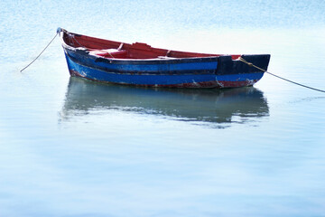 Naklejka premium Not a breath of wind today. Shot of an empty fishing boat floating on calm waters.