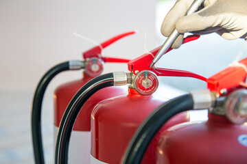 Close up fire extinguisher and firefighter checking pressure gauge level for protection and prevent and safety rescue and use of equipment on fire training concept.