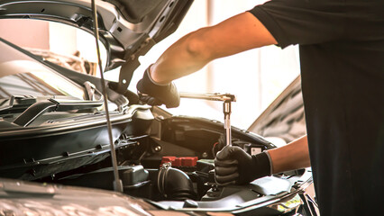 Close-up hand auto mechanic using the wrench to repairing car engine problem. Concepts of check and...