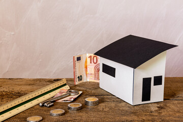 Konzept zur Finanzierung einer Immobilie: Gebäudemodell, Geldmünzen und -scheine, Schlüssel, Maßstab