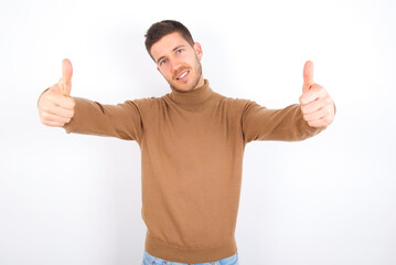 young caucasian man wearing grey turtleneck over white background approving doing positive gesture with hand, thumbs up smiling and happy for success. Winner gesture.
