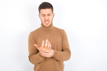young caucasian man wearing grey turtleneck over white background Suffering pain on hands and...