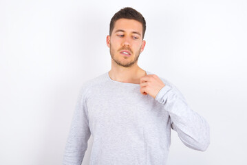 young caucasian man wearing grey sweater over white background stressed, anxious, tired and frustrated, pulling shirt neck, looking frustrated with problem