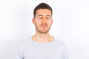 Obraz premium young caucasian man wearing grey sweater over white background nice-looking sweet charming cute attractive lovely winsome sweet peaceful closed eyes