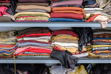 Multicolored various clothes stacked in piles on a shelf in a atelier
